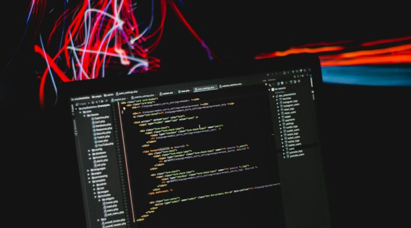 Laptop mit Programmcode vor bunten Lichtspuren – kostenlose Software